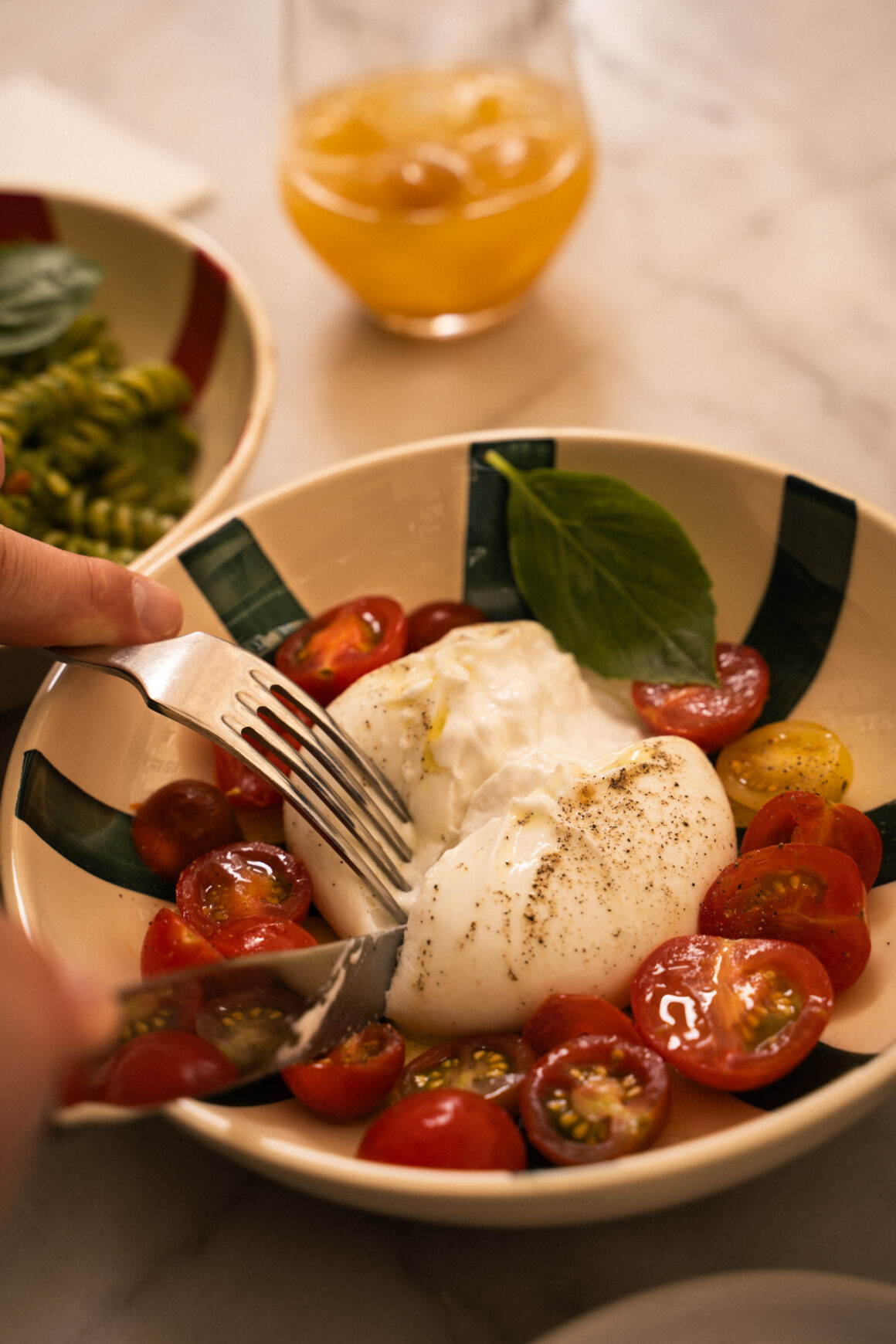 Photographie culinaire en gros plan d'une burrata fraîchement coupée avec des tomates cerises dans un bol en céramique artisanale, style lifestyle pour restaurant.