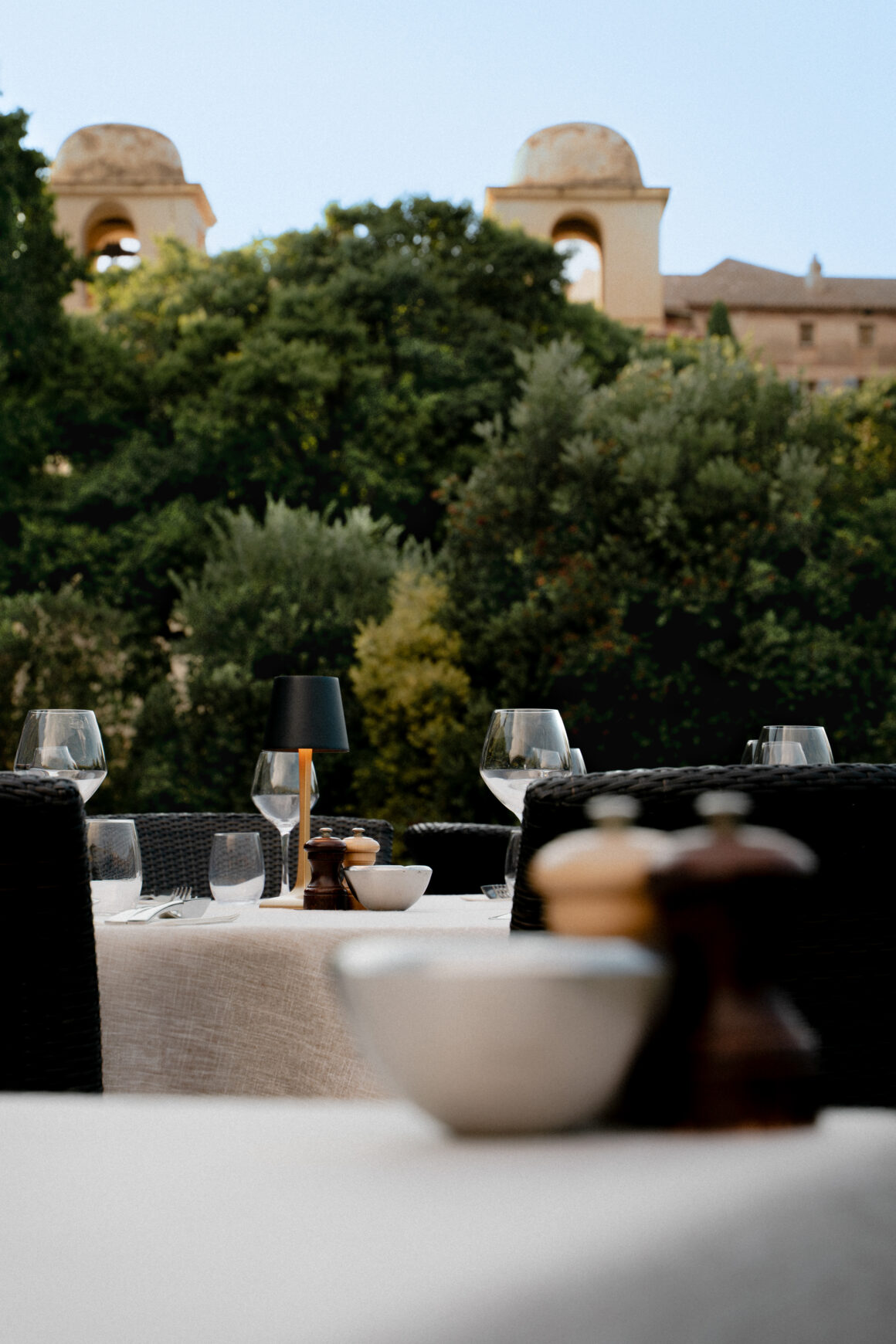 Table dressée à A Mandria di Pigna et vue sur l'Eglise du village de Pigna, photographie culinaire et art de vivre dans un établissement de caractère en Balagne, Corse.