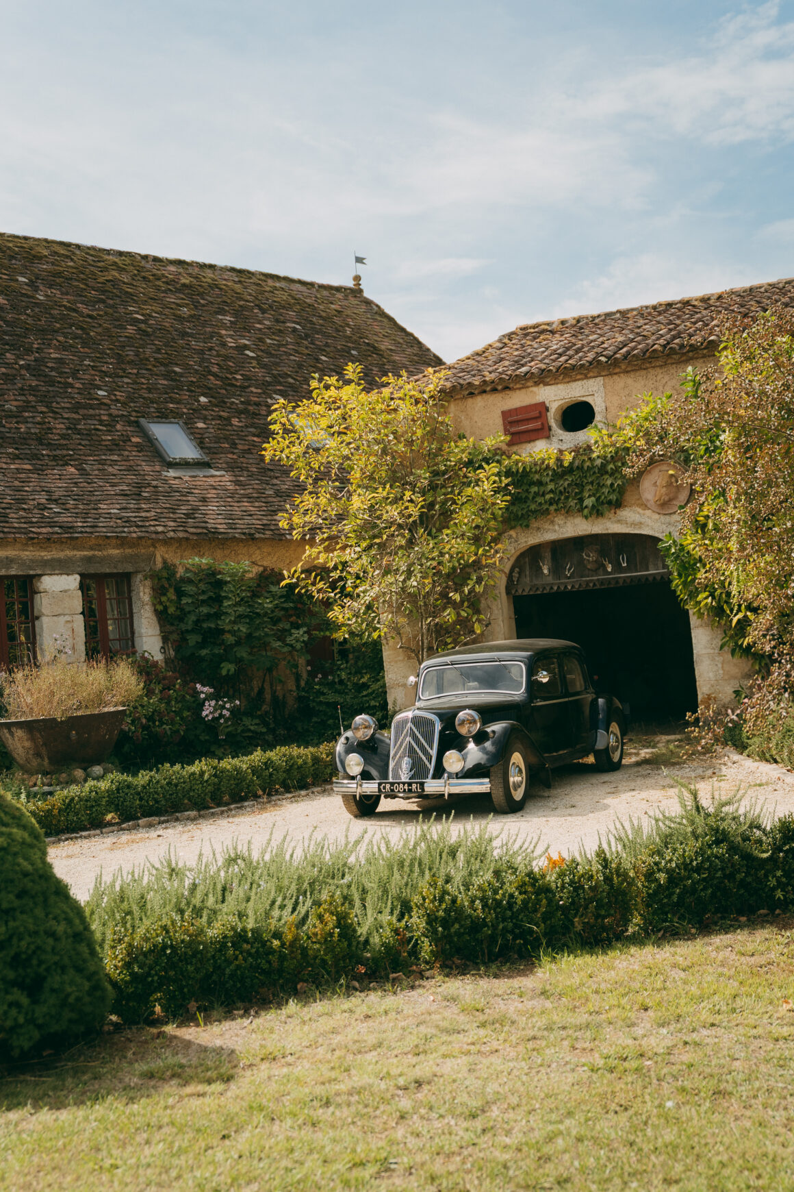 Citroën Traction Avant devant les bâtiments en pierre du Domaine de Lavernelle, dans le Périgord.
