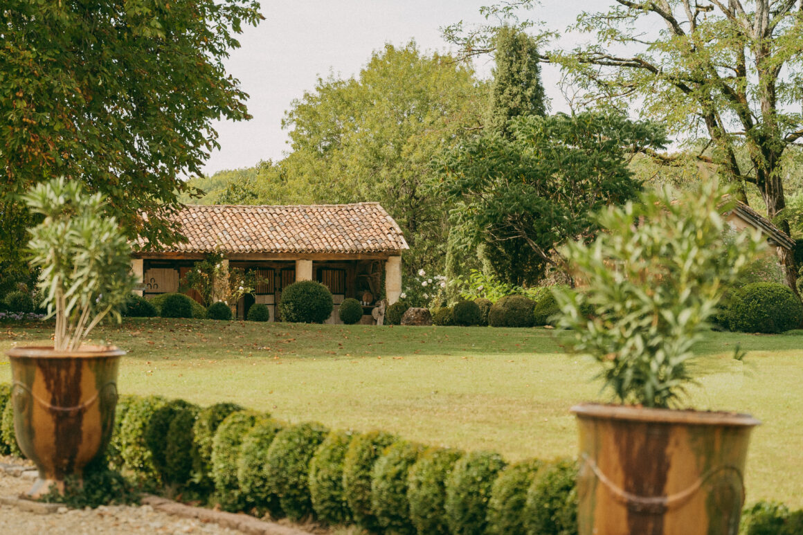 Anciennes écuries en pierre et toiture en tuiles, entourées d’un jardin paysager au Domaine de Lavernelle.