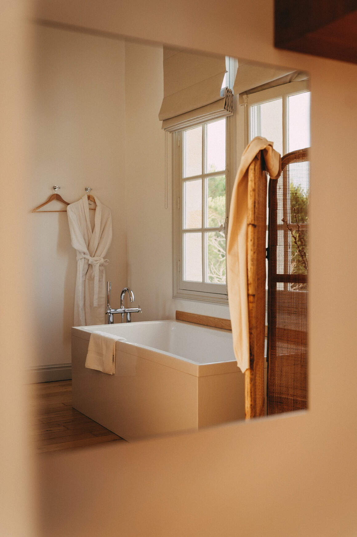 Salle de bain du Château Larteau en Gironde, avec baignoire, peignoir et paravent en cannage.