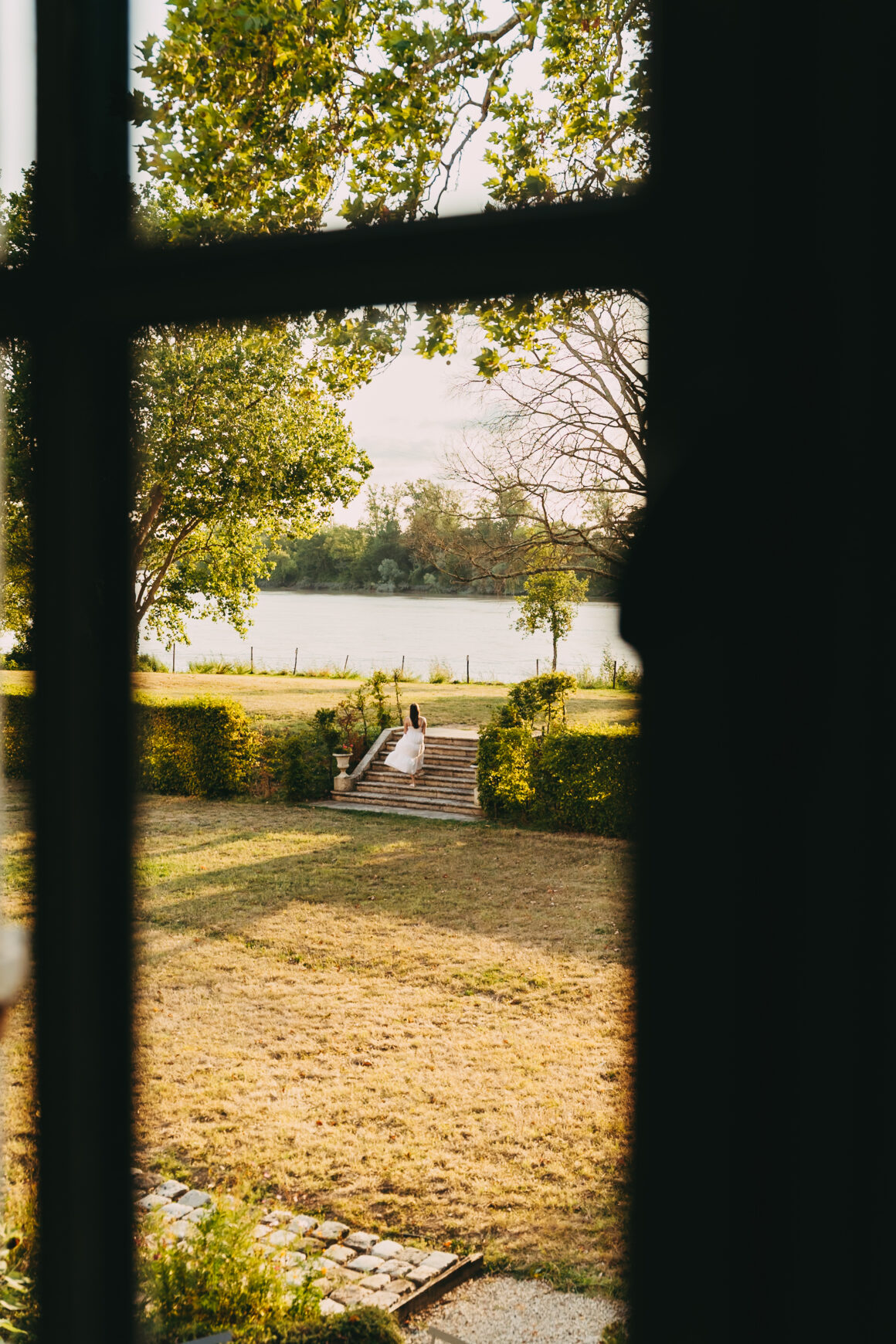Vue depuis le Château Larteau sur le jardin et la Garonne, avec une femme assise sur les marches.