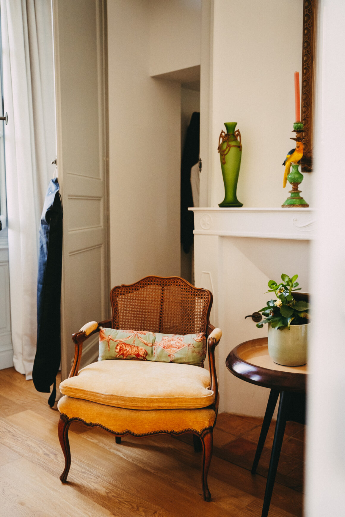 Fauteuil ancien près d’une cheminée, vase vert et objets décoratifs dans une chambre du Château Larteau.