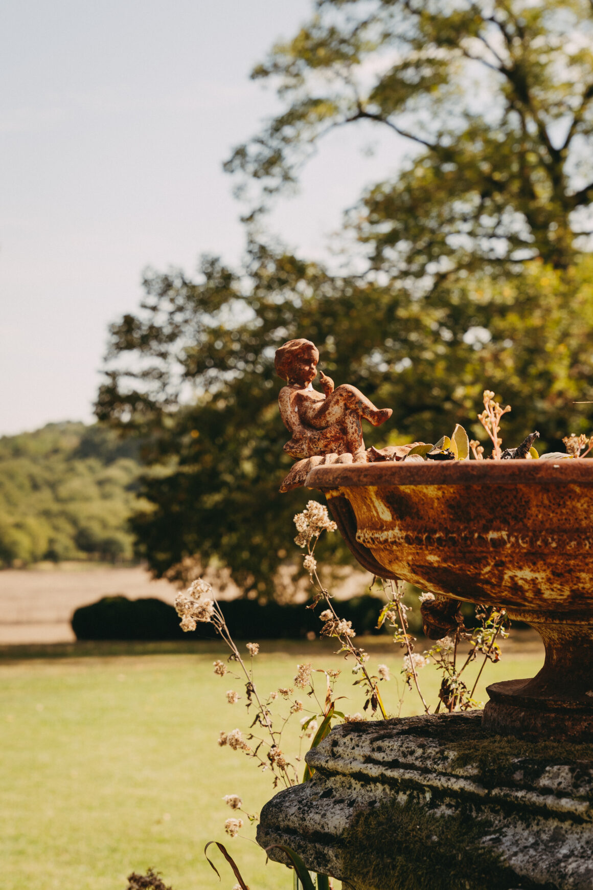 Détail d’une fontaine ancienne en métal rouillé, ornée de petites figures sculptées, dans le jardin du Domaine de Lavernelle.