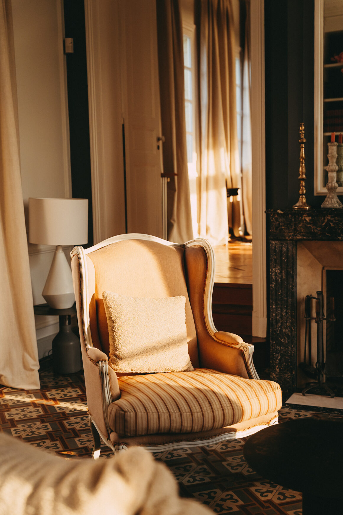 Fauteuil ancien éclairé par la lumière naturelle dans le salon du Château Larteau à Arsac.