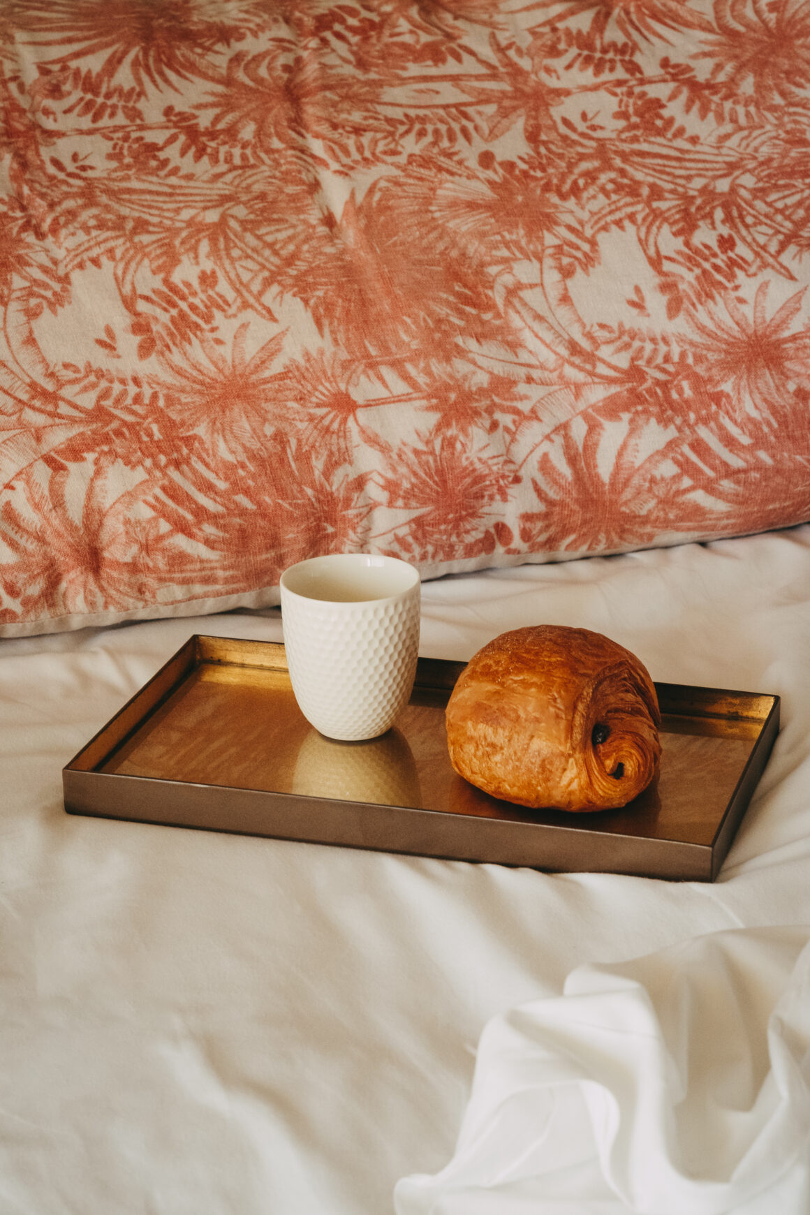 Petit-déjeuner servi en chambre avec chocolatine et tasse sur un plateau