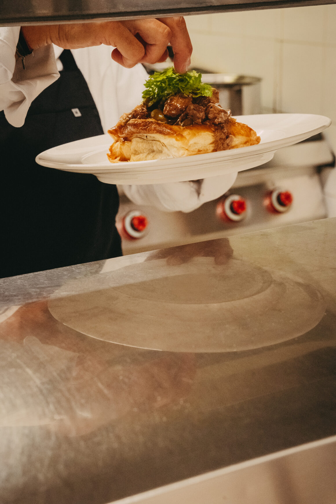 Chef dressant une assiette en cuisine au restaurant A Mandria di Pigna en Balagne
