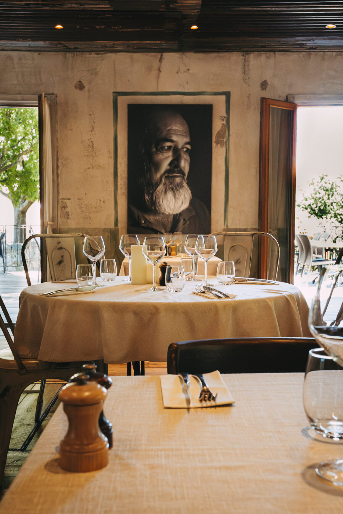 Salle du restaurant A Mandria di Pigna avec tables dressées et terrasse en arrière-plan