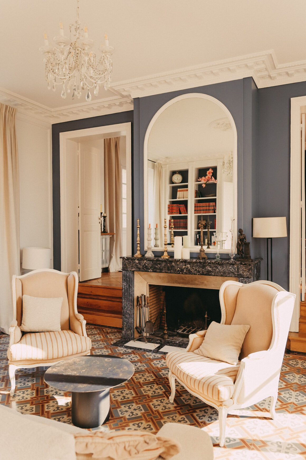 Salon du Château Larteau à Arsac, près de Bordeaux, avec cheminée en marbre, grand miroir et fauteuils anciens.