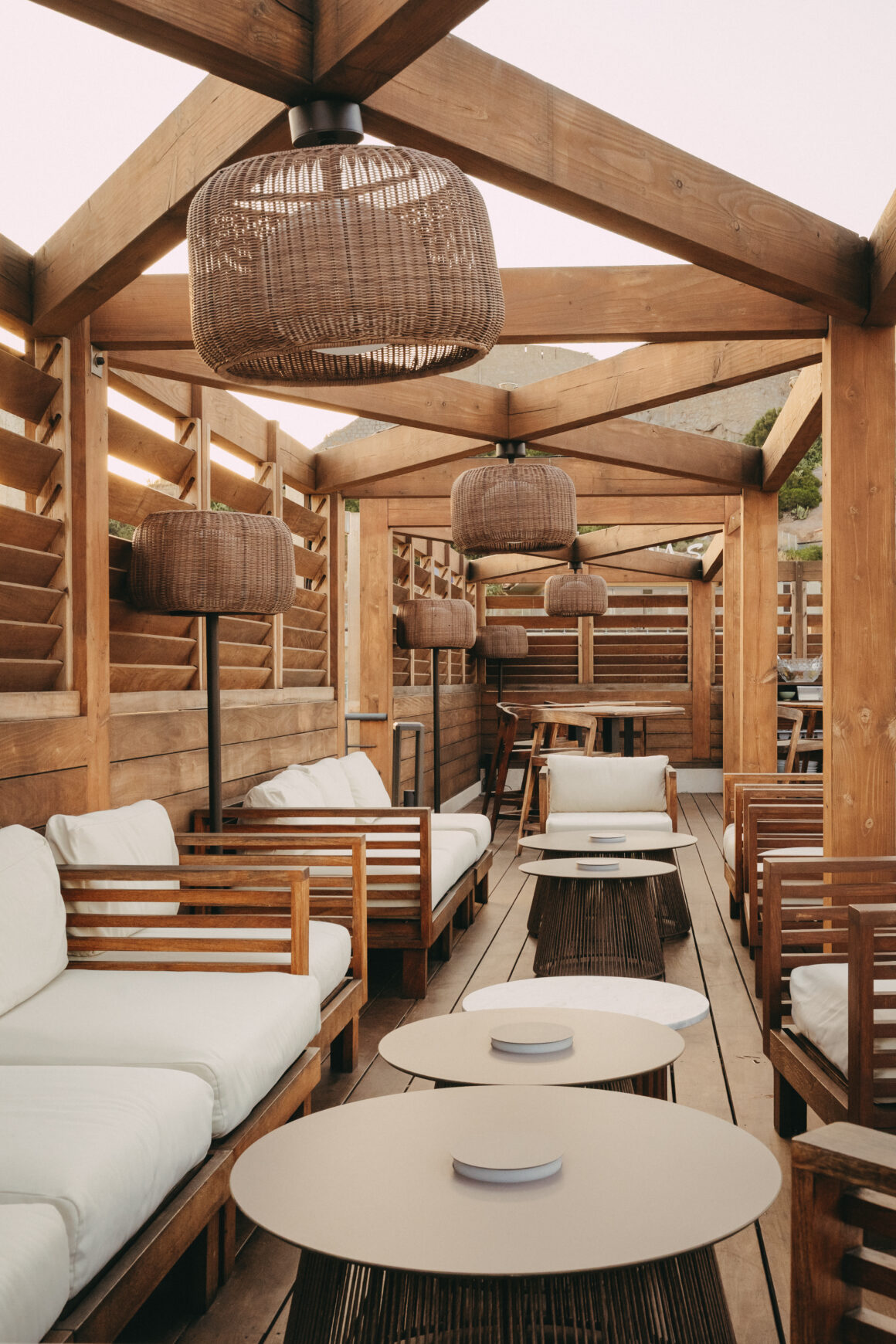 Terrasse d’hôtel à Calvi aménagée de mobilier en bois et de suspensions en fibres naturelles