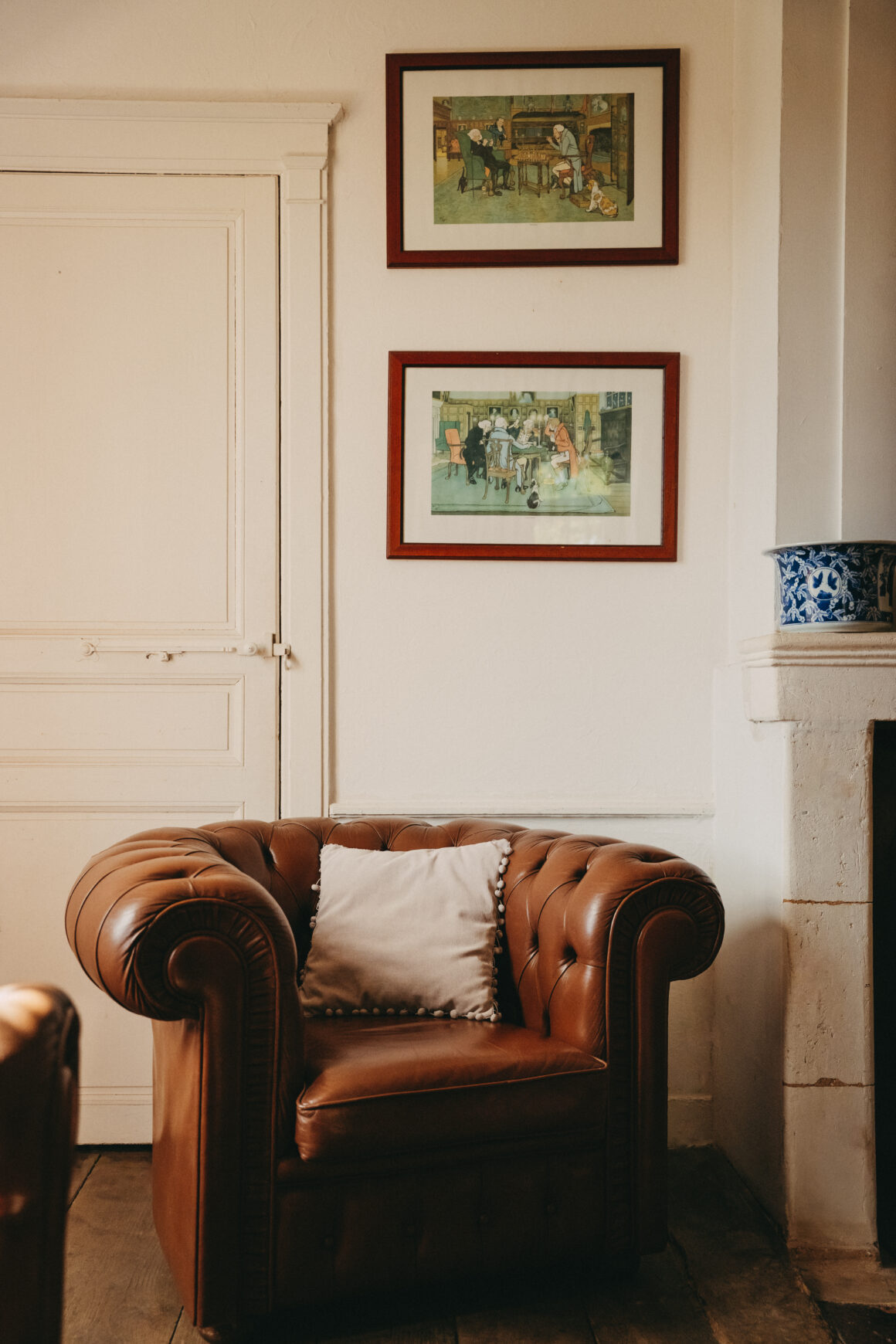 Fauteuil Chesterfield en cuir brun, accompagné d’un coussin écru, dans un salon du Domaine de Lavernelle en Dordogne.